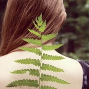 chica de espalda con una rama de hojas asemejando ser su columna vertebral
