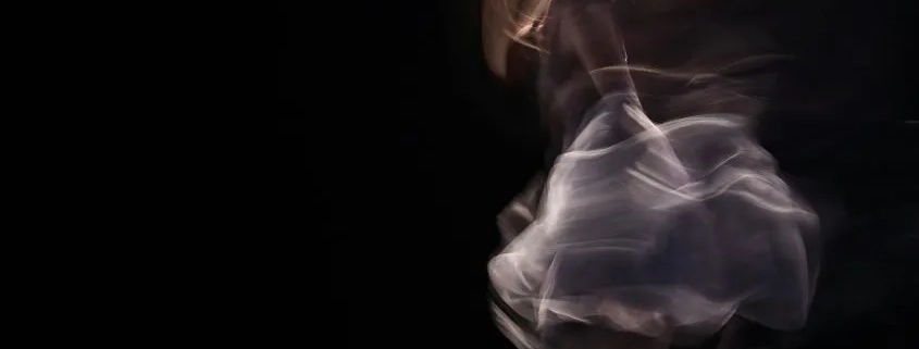 foto en larga exposición de una mujer bailando en un escenario oscuro