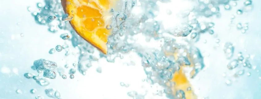trozo de naranja flotando entre las burbujas de una bebida
