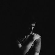 chico en fondo negro tocandose el hombro porque le duele