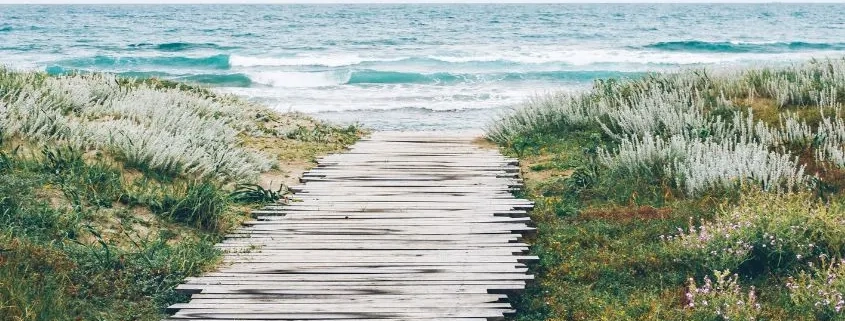 una pasarela de madera que lleva a una playa